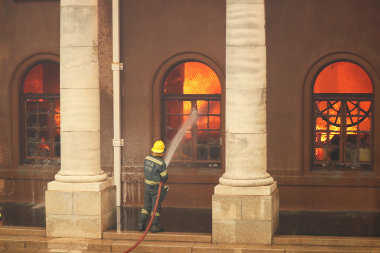 Firefighters battle flames at the University of Cape Town's library after a bushfire broke out on the slopes of Table Mountain in Cape Town, South Africa, on April 18, 2021.