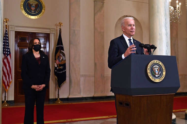 Joe Biden speaks at the White House behind official podium, Kamala Harris stands nearby with a black facemask on