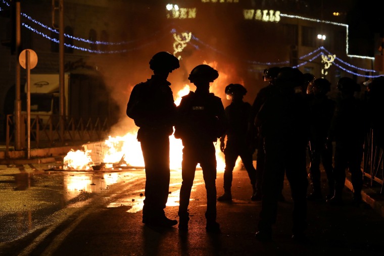 Image: Israeli police officers stand next to a burning barricade during clashes with Palestinians, as the Muslim holy fasting month of Ramadan continues, in Jerusalem