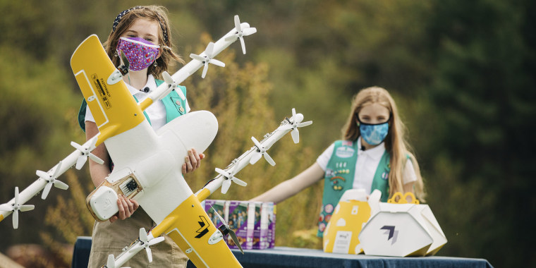 Girl Scouts Alice Goerlich, right, and Gracie Walker pose with a Wing delivery drone in Christiansburg, Va. The company is testing drone delivery of Girl Scout cookies in the area.