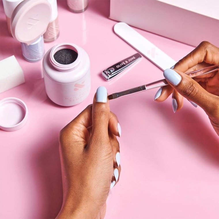 Woman giving herself a manicure using a Olive &amp; June Manicure set