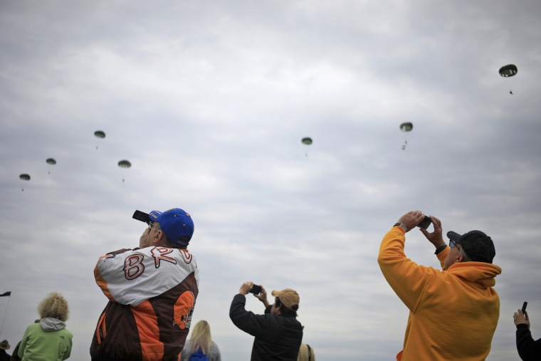 Spectators take photos as parachutists descend on the drop zone.