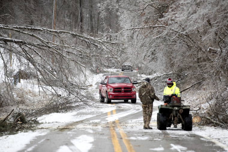 Vehicles navigate through downed trees along Blue Sulpher Road on Feb. 16, 2021