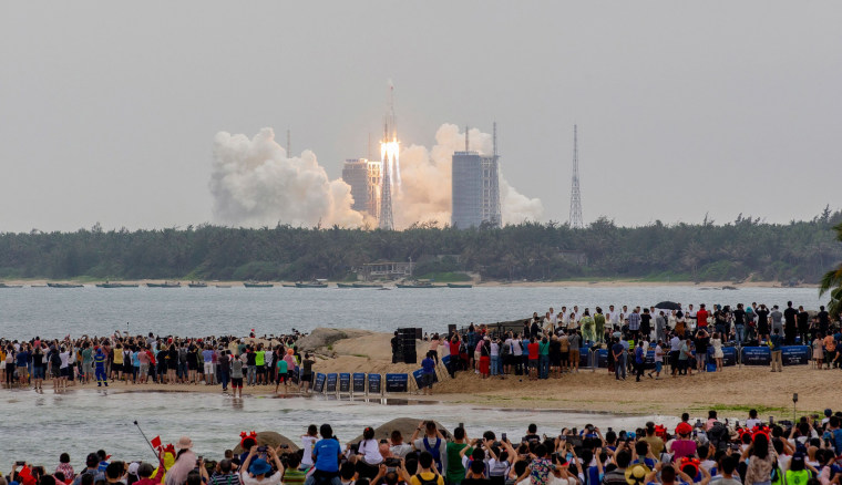 Image: People watch a Long March 5B rocket, which carries China's Tianhe space station core module, lifting off from the Wenchang Space Launch Center, in southern China's Hainan province