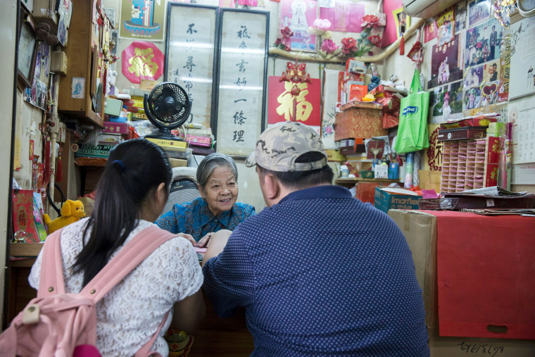 Image: A fortune teller with customers at a stall near the Wong Tai Sin Temple in Hong Kong.