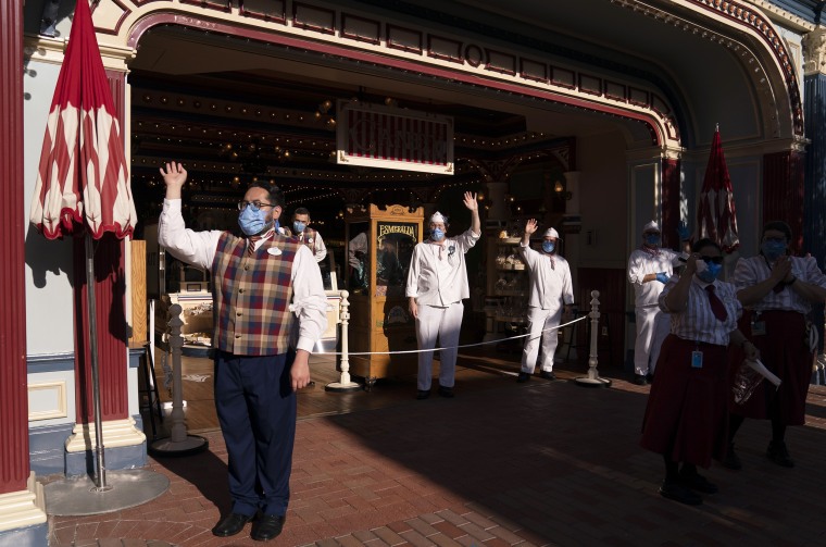 Image: Employees wave as guests walk along Main Street USA at Disneyland in Anaheim, Calif., on April 30, 2021.