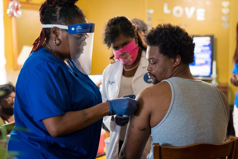 Keshawn Shaw looks at his arm where nurse Andretta Griffin, left, and Dr. Karen Smith, center, administered a Covid-19 vaccination at his grandmother Bessie Bratcher's home in Raeford, N.C.