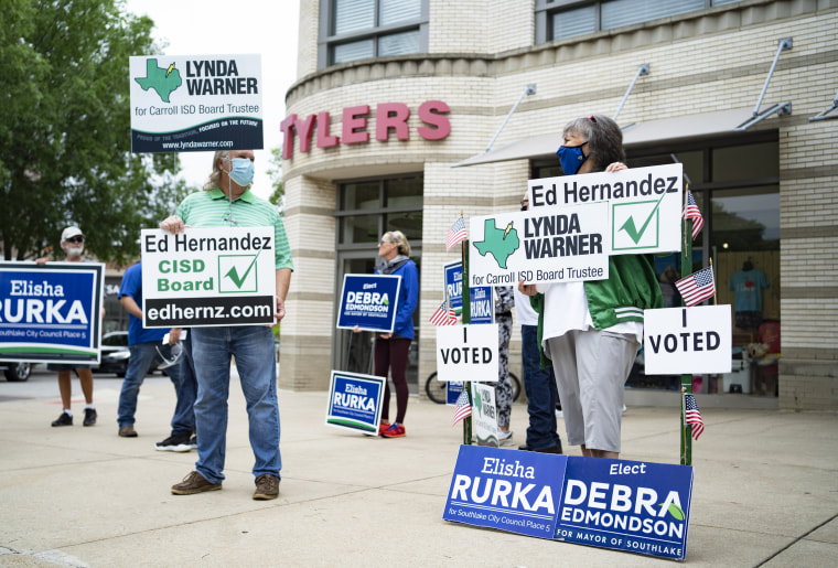 IMAGE: People hold campaign signs in municipal elections in Southlake, Texas, on May 1, 2021.