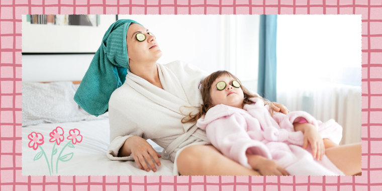 Mother and young daughter cleaning back on bed, wearing robes, towels on their heads and using cucumbers over their eyes