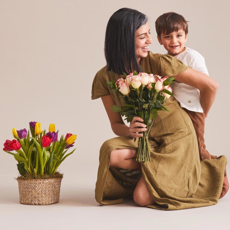 Mom hugging her son while holding flowers