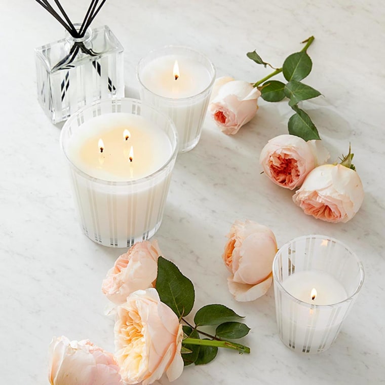 Image of white candles from Nest surrounded by roses