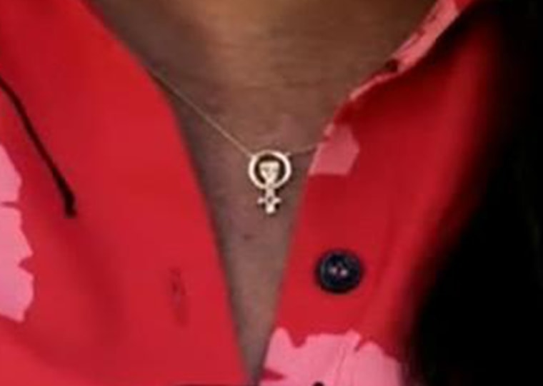 Markle wore Awe Inspired's $140 charm necklace, featuring a pendant with the symbol for female alongside of a raised fist.