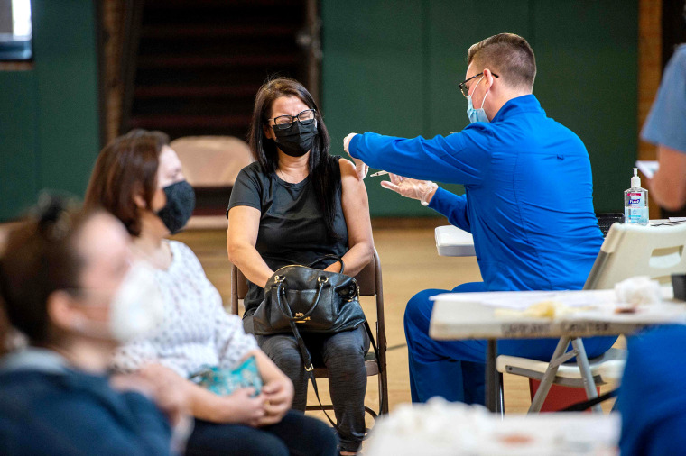 Image: A woman squints as she receives her second dose of the Moderna Covid-19 vaccine at the mobile Covid-19 vaccination clinic at Saint Charles Borromeo Catholic Church's McGivney community center in Bridgeport, Conn., on April 20, 2021.