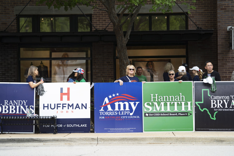 People hold campaign posters for various candidates in municipal elections in Southlake, Texas, on May 1, 2021.