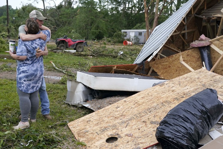 Image: A neighbor hugs Vickie Savell next to the remains of her new mobile home early on May 3, 2021, in Yazoo County, Miss.