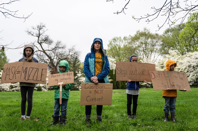 Image: A mother and her children hold anti-vaccination and anti-Covid19 mandate signs in protest on state capitol grounds on April 14, 2021 in Frankfort