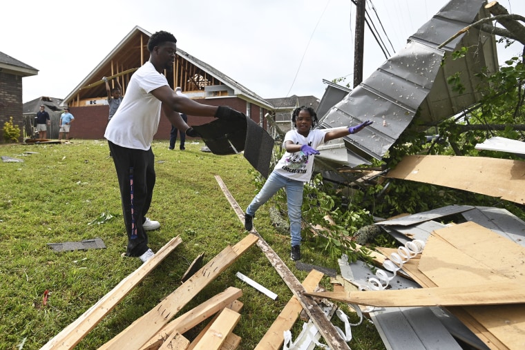 Derrick Pounds and his daughter Madison clean up debris around their residence on Elvis Presley Drive in Tupelo, Miss., on May 3, 2021.