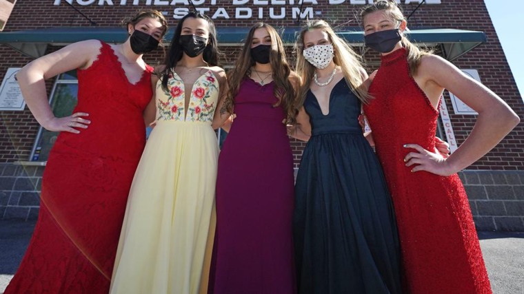 While wearing their prom gowns, students pose for a photograph in the outfield at the New Hampshire Fisher Cats minor league baseball stadium in Manchester, N.H., on Monday, April 26, 2021.