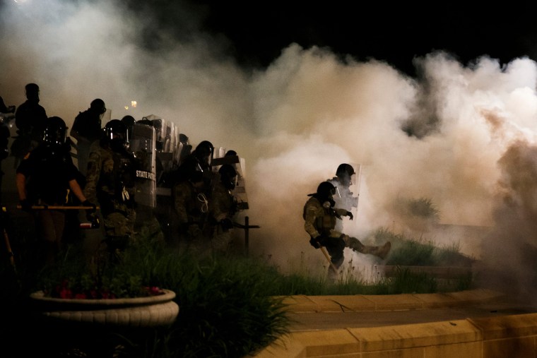 Image: Officers stand in a cloud of tear gas as protesters retreat on the steps of the Iowa State Capitol on May 30, 2020 in Des Moines.