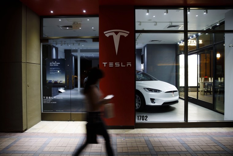 Image: A pedestrian walks past a Tesla store in Palm Desert, Calif, on March 7, 2019.