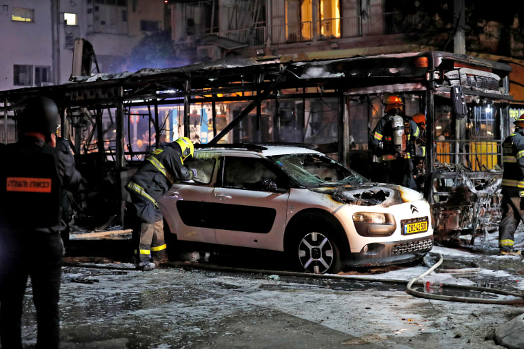 Image: Israeli firefighters check out damaged vehicles in the Israeli town of Holon near Tel Aviv, on May 11, 2021, after rockets are launched towards Israel from the Gaza Strip controlled by the Palestinian Hamas movement.