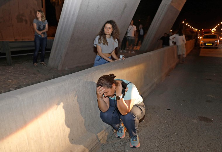 Image: People take cover under a bridge at the entrance of Israel's central city of Tel Aviv,