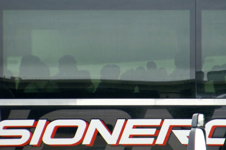 Image: Minors who migrated to the U.S. without their parents wait on buses in a parking lot outside the Kay Bailey Hutchison Convention Center in Dallas.