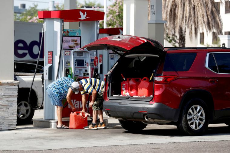 Image: A couple fills up multiple 5 gallon gas tanks at a Wawa gas station, run by Colonial Pipeline, in Tampa, Fla., on May 12, 2021.