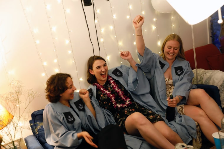 Image: Erin Neil and her roommates, Kayla and Zoe, pop a bottle of champagne following their virtual graduation ceremony in New York City on April 29, 2021.