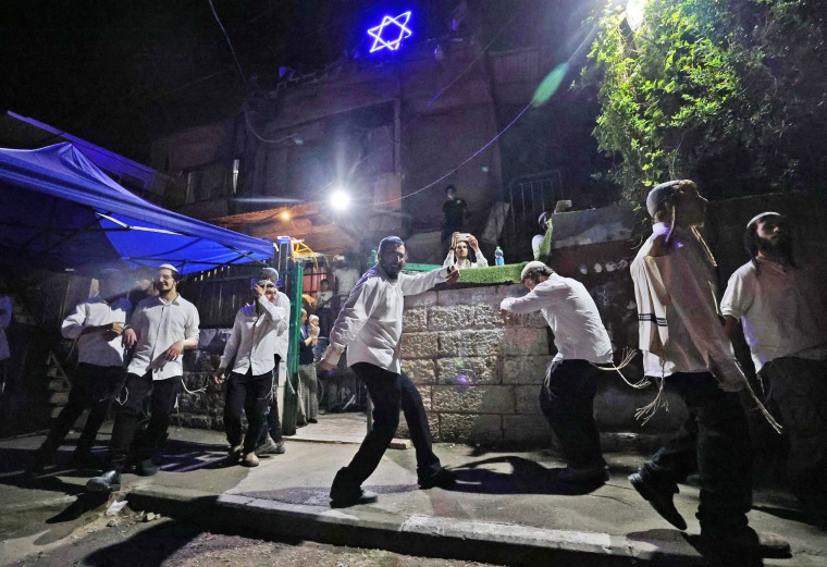 Israeli settlers dance in front of a house decorated with the Star of David in the Sheikh Jarrah neighborhood of Israeli-annexed east Jerusalem on May 9, 2021.