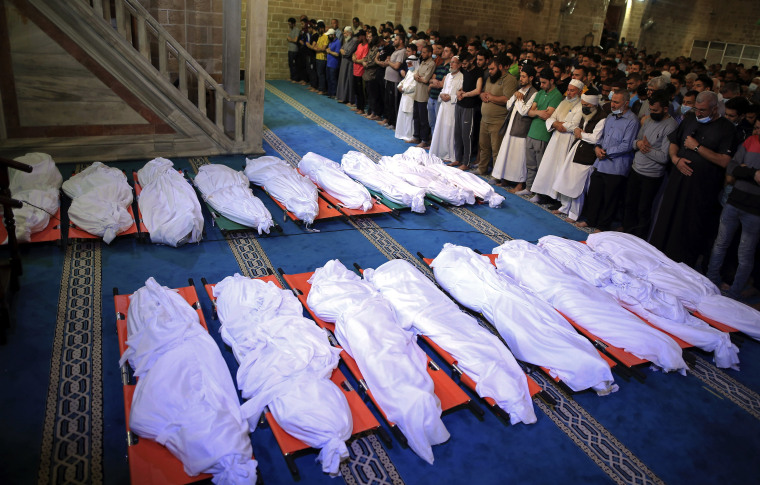 Mourners pray over the bodies of 17 Palestinians who were killed in overnight Israeli airstrikes in Gaza City on May 16, 2021.