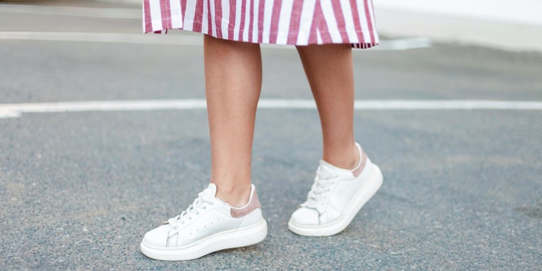 Woman wearing a pink and white striped dress with white sneakers