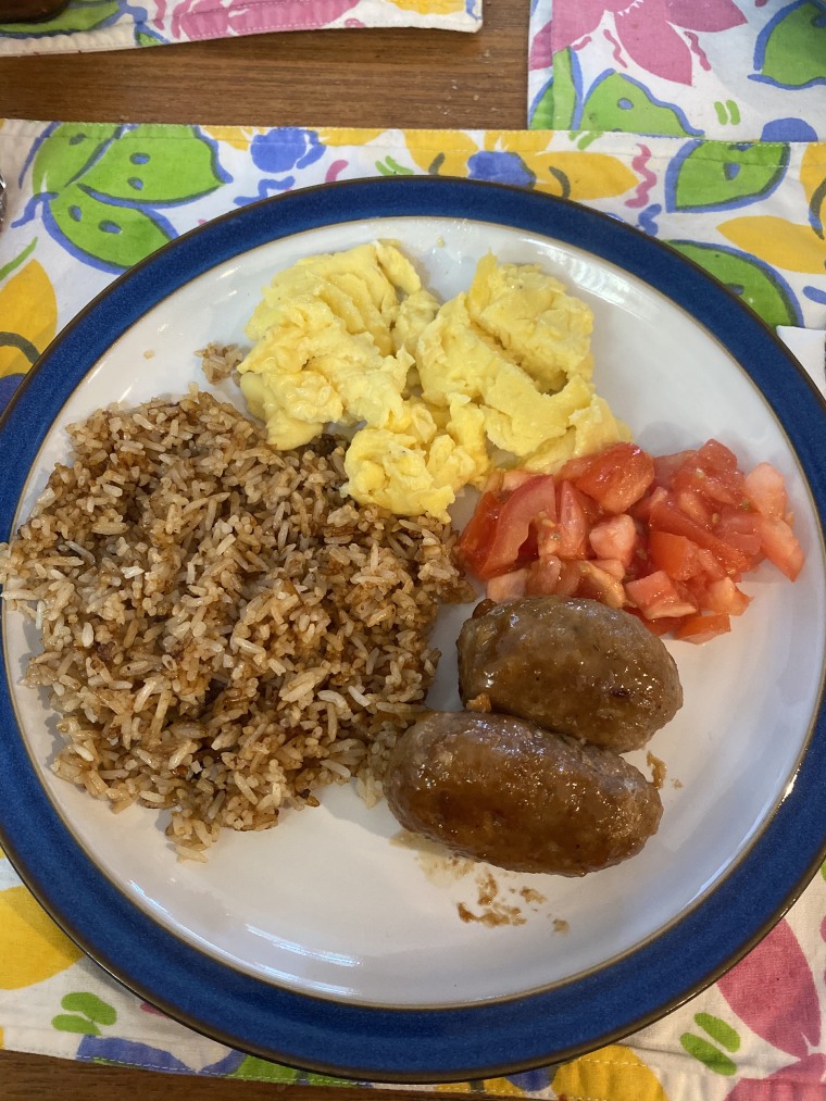 A traditional Filipino breakfast with garlic fried rice, eggs, longganisa and tomato.