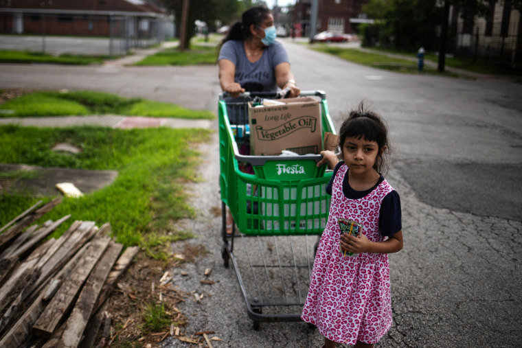 Image: A young girl helps pull a cart with groceries distributed by the Wesley Community Center to residents affected by the economic fallout caused by Covid-19 in Houston, Texas, on July 24, 2020.