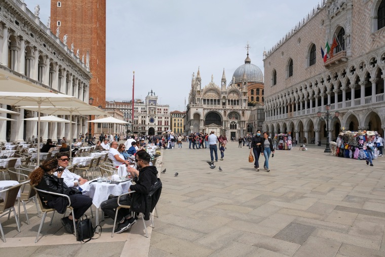 Image: People sit at outdoor tables at St. Mark's Square as Italy lifts quarantine restrictions for travelers in Venice, Italy