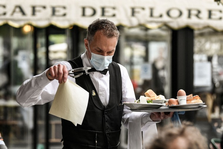 Image: A waiter works at the terrace of Paris' landmark Cafe de Flore