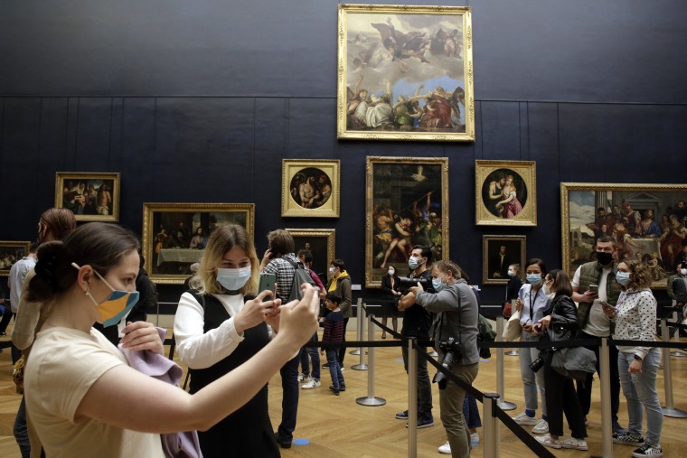 Image: People take snapshots as they visit the Louvre in Paris.