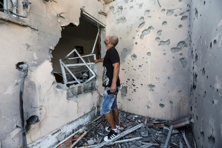 Image: Buchbut looks at his damaged house after it was hit with a rocket fired from Gaza to Sderot, Israel