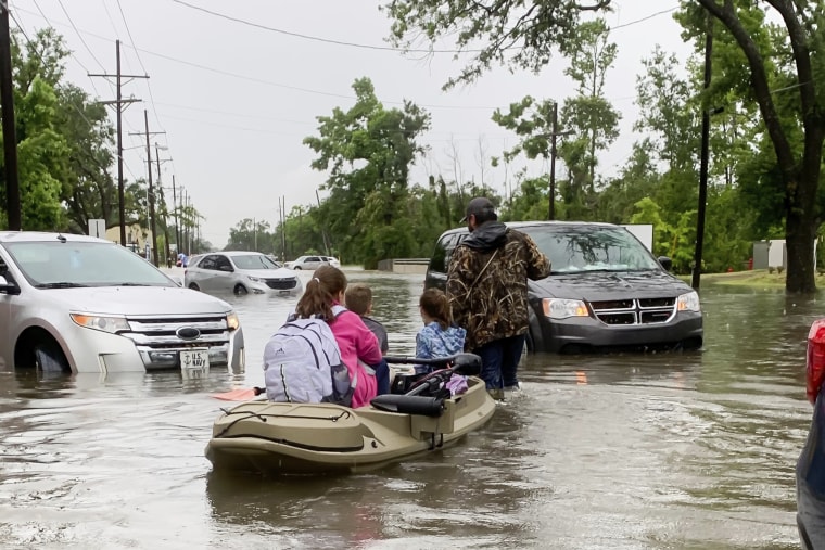 Parents use boats to pick up students from schools after nearly a foot of rain fell in Lake Charles, La., on May 17, 2021.