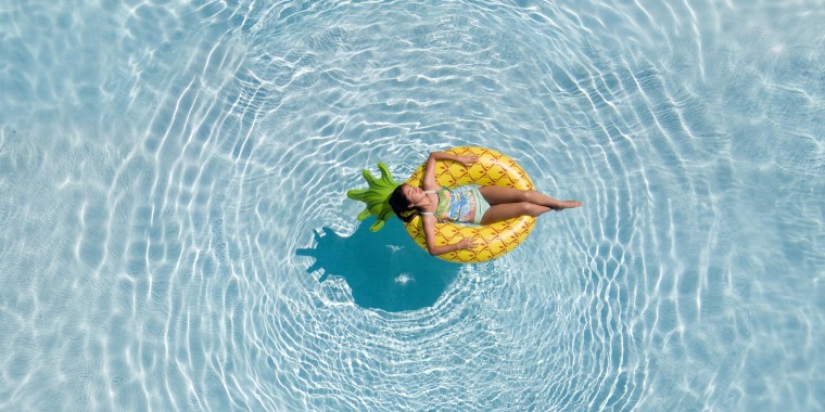 An aerial view of teenage girl relaxing in the swimming pool on a pineapple floatie