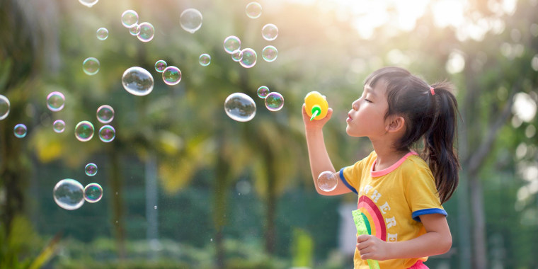 Little girl playing with bubbles outside
