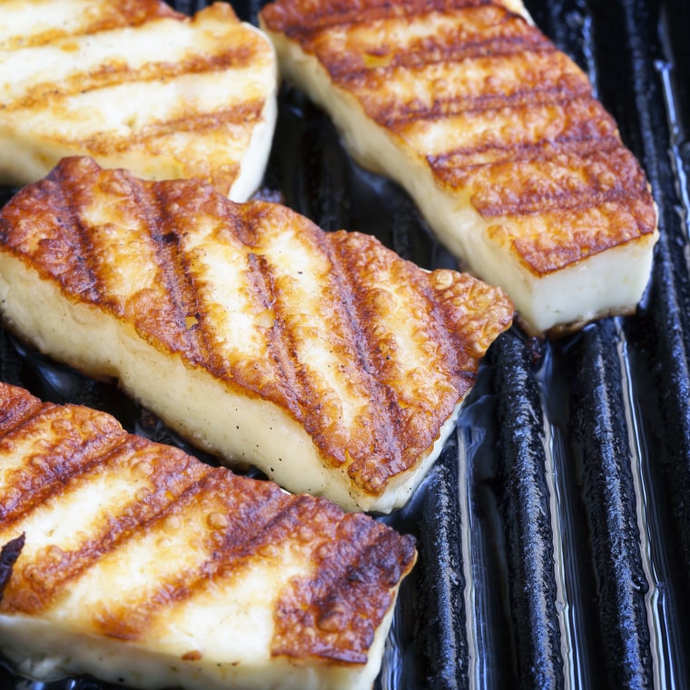 Halloumi cheese frying in a grill pan.
