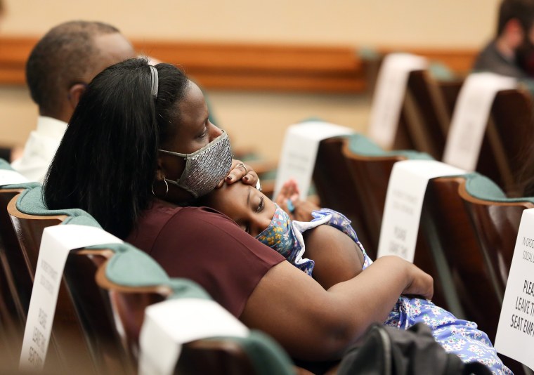 Image: Sharde Butler holds her daughter, Malia, 6, in the overflow room of a hearing in Austin on March 30, 2021.