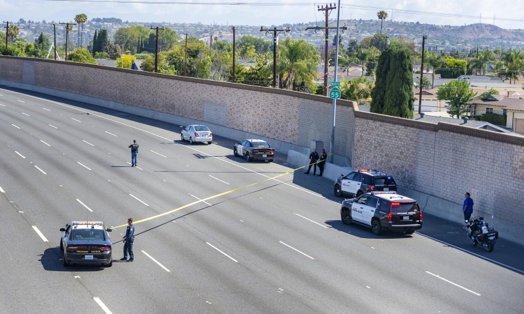 Image: Yellow crime scene tape stretches across the northbound lanes of the 55 freeway as police investigators walk the freeway looking for evidence following a shooting on May 21, 2021 in Orange, Calif.