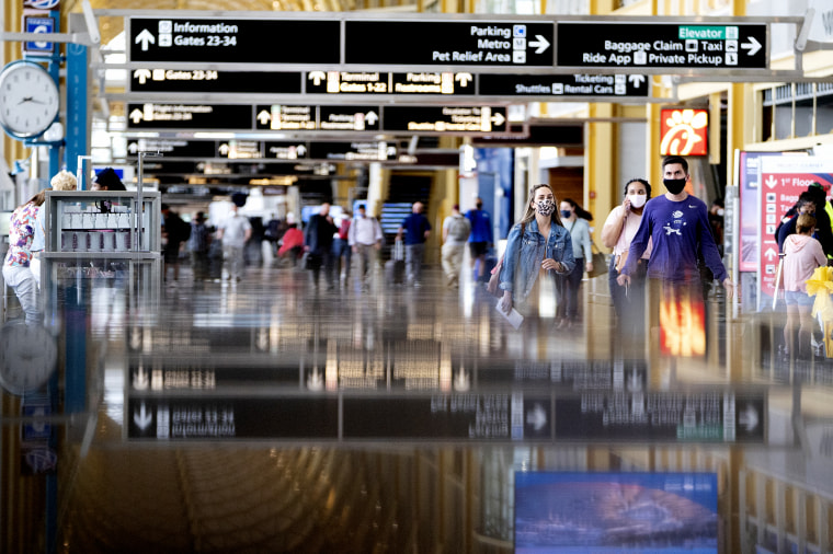 Travelers wearing protective masks walk through Ronald Reagan National Airport (DCA) in Arlington, Va., on May 25, 2021.