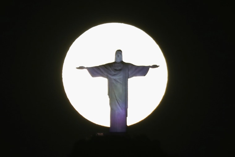 The Super Flower Blood Moon shines behind the Christ the Redeemer statue in Rio de Janeiro on May 26, 2021.