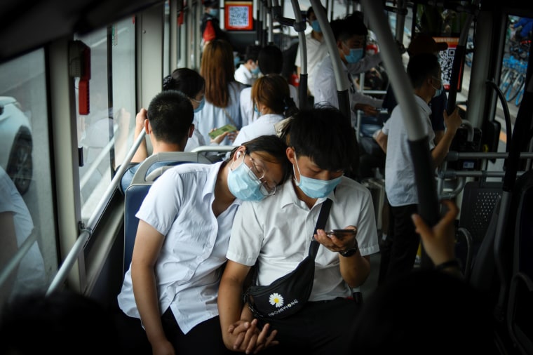 Image: A couple wearing face mask ride on a bus during rush hour in Beijing