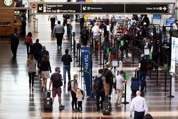 Travelers walk through the concourse with their luggage at Ronald Reagan Washington National Airport on May 25, 2021, in Arlington, Va.