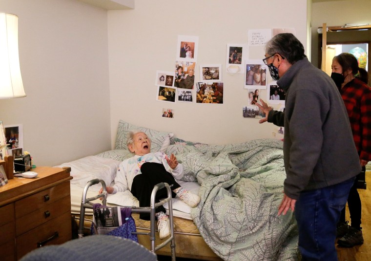Image: Uomoto, 98, reacts as son Uomoto and niece Yamada surprise her with their first in-person visit in a year at Nikkei Manor, an assisted living facility in Seattle