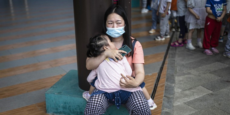 A woman carries her sleeping child at a community square